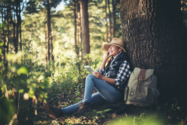 young woman listening to music from smartphone under the tree in the garden. - Photo, image