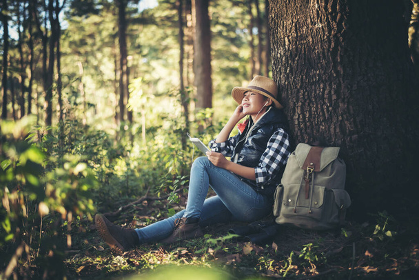 nuori nainen kuuntelee musiikkia älypuhelimesta puun alla puutarhassa. - Valokuva, kuva