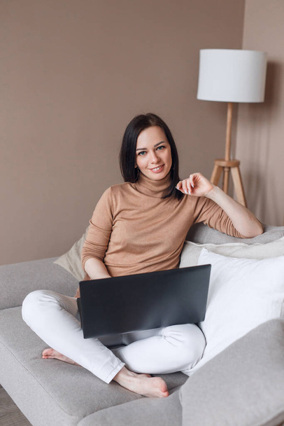 Smiling businesswoman sitting on comfortable sofa at home with computer. - Photo, Image