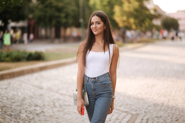 Attractive young woman walking by herself in centre of city in summer time. Woman walk alone. Happy woman outdoors. Social distancing - Foto, Imagen