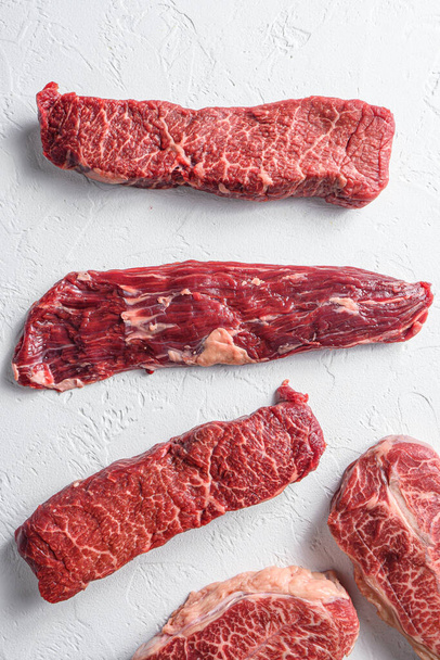 Rauwe biologische machete biefstuk in de buurt van denver en top blade marmer rundvlees op witte achtergrond bovenaanzicht close-up - Foto, afbeelding