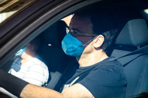 Man with his wife on background wearing protective mask driving. Mature couple wearing protective mask driving. - Photo, Image
