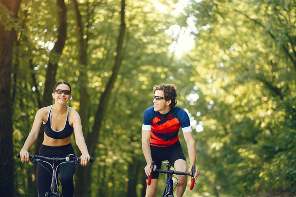 Sports couple riding bikes in summer forest - Fotoğraf, Görsel