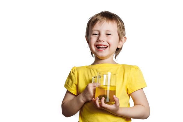 Cute little Girl dressed in yellow t-shirt holding a mug with lemon tea. - Фото, изображение