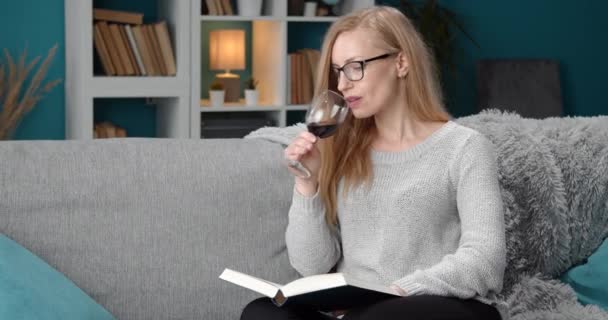 Beautiful woman drinking red wine while reading book at home - Felvétel, videó