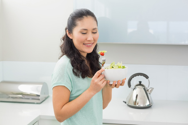 Smiling woman with a bowl of salad in kitchen - Foto, Imagem