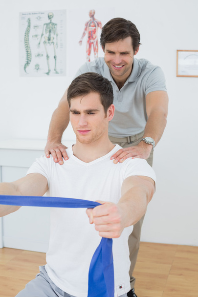 Male therapist assisting man with exercises in office - Valokuva, kuva
