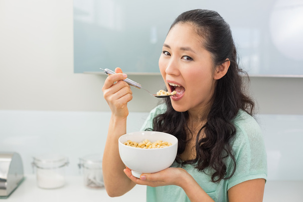 Young woman eating cereals in kitchen - Foto, Imagen