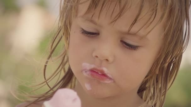 Suloinen pieni tyttö syö jäätelöä rannalla, hidastettuna
 - Materiaali, video