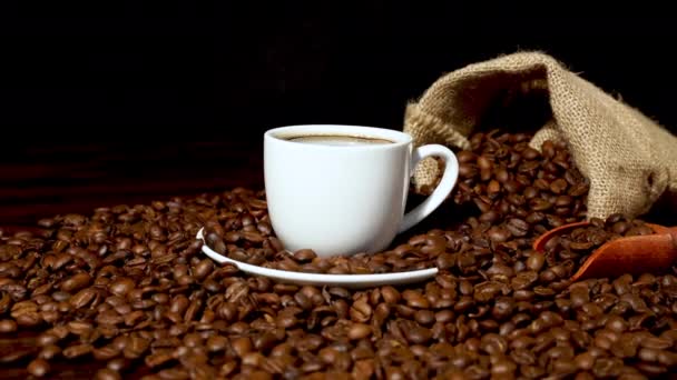 Φρέσκος καφές μέσα σε λευκό φλιτζάνι καφέ και κόκκους καφέ  - Πλάνα, βίντεο