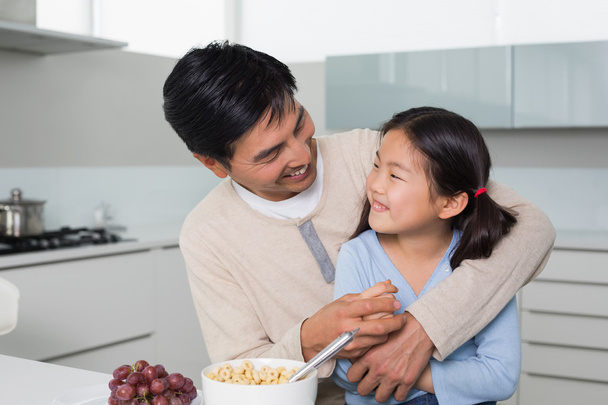 Cheerful father with daughter having cereals in kitchen - Photo, image