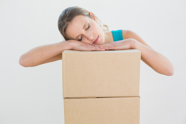Pretty young woman resting head over a stack of boxes - Foto, Bild