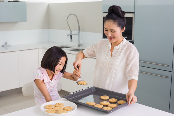 Girl helping her mother prepare cookies in kitchen - Фото, зображення