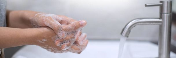 Πλένει τα χέρια τρίβοντας με σαπούνι κατάλληλη τεχνική κάτω από το νεροχύτη μπάνιο για αντιβακτηριακή επιδημία Prevent coronavirus (covid-19). Πρόληψη της γρίπης - Φωτογραφία, εικόνα