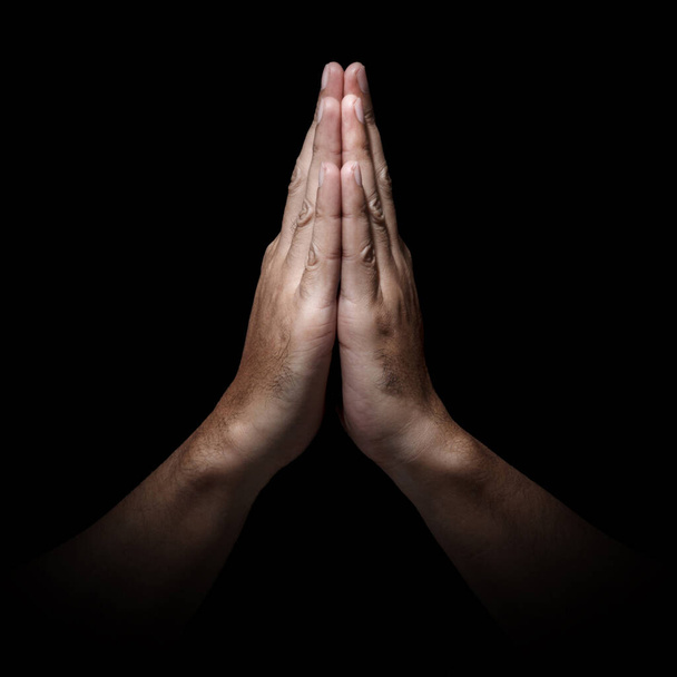 Les mains de l'homme en position de prière image basse clé. Contraste élevé isolé sur fond noir. Rapport 1 : 1
 - Photo, image