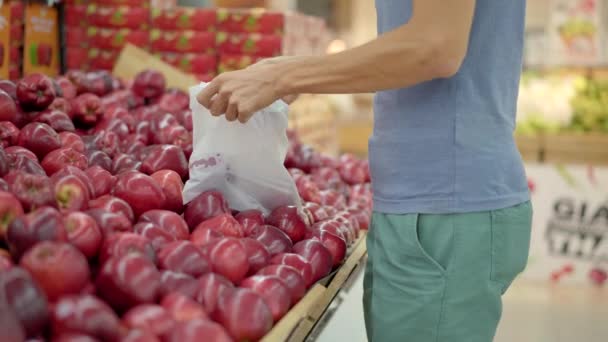 An alarmed man wears a medical mask against coronavirus while purchasing food in a supermarket or store. Quarantine is over, now you can go to the clothing store but have to wear a face mask. Health - Кадры, видео