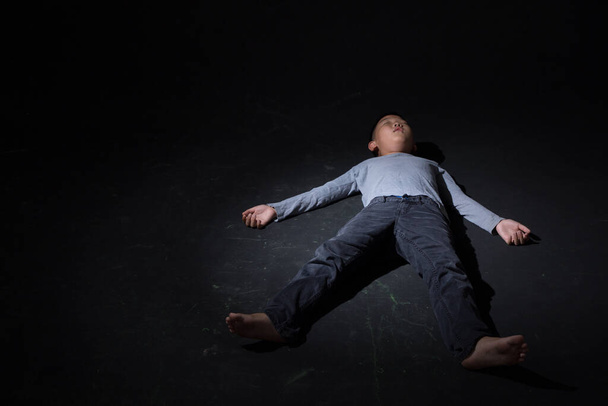 Asian Boy Slapen op de vloer op zwarte achtergrond. Concept: Depressief. Teleurgesteld. Emotie. Kopieer ruimte.. - Foto, afbeelding