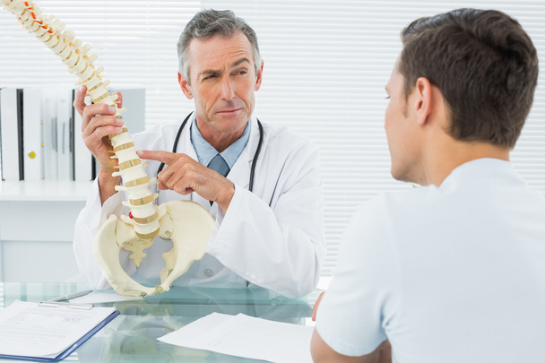 Doctor explaining spine to a patient in office - Fotoğraf, Görsel