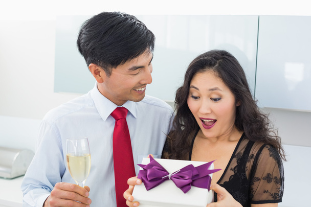 Shocked woman opening a gift box by man with champagne - Fotó, kép