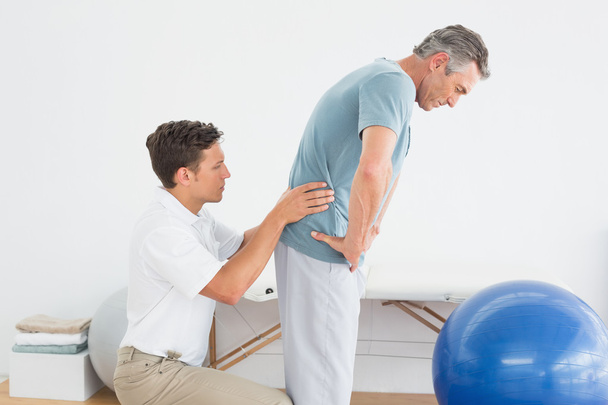 Therapist massaging mans lower back in gym hospital - Photo, Image