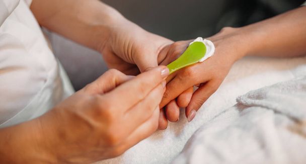 Kaukasische masseur het aanbrengen van een speciale crème op de klanten hand voor het starten van de hand massage procedure - Foto, afbeelding