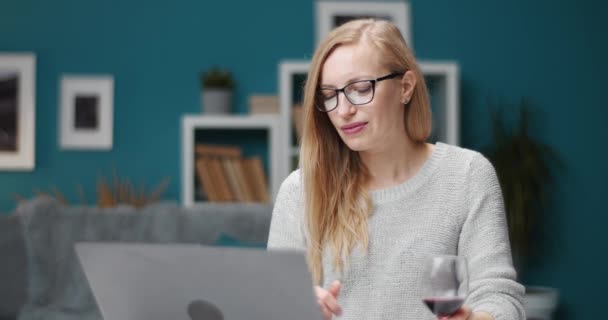 Charming woman working on laptop and drinking red wine - Footage, Video