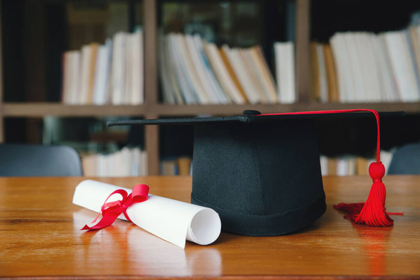 Graduation cap with Degree on wood table and Books step in Library room,Education concept - Фото, зображення