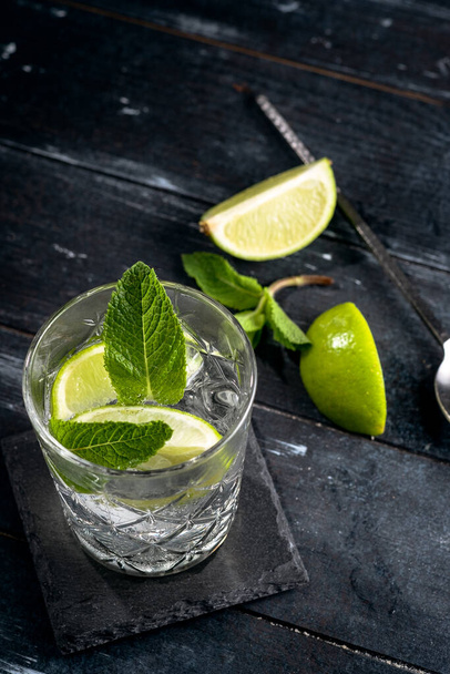 Джин с чистой водой и льдом в стакане - алкогольный коктейль с лаймом и мятой
 - Фото, изображение