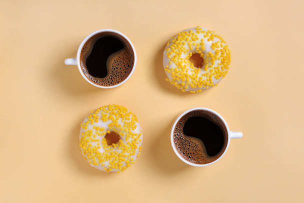 Two yellow donuts and coffee on color background, top view - Photo, Image