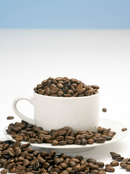 Ψητά φασόλια καφέ σε λευκό κύπελλο και πιατάκι - Φωτογραφία, εικόνα