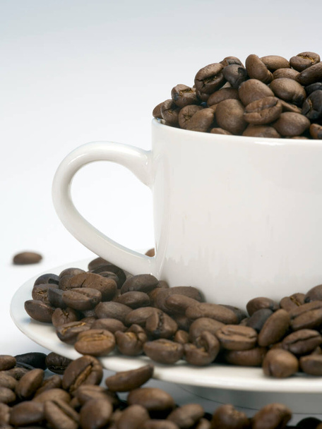 Ψητά φασόλια καφέ σε λευκό κύπελλο και πιατάκι - Φωτογραφία, εικόνα