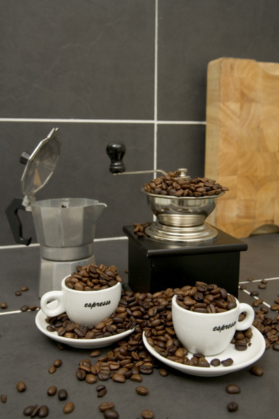 タイル張りのキッチンワーク表面にローストコーヒー豆、エスプレッソカップとグラインダーの静物画 - 写真・画像