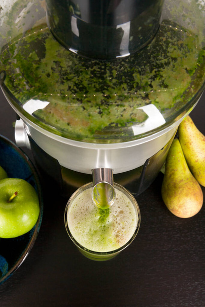Une presse-agrumes versant du jus de fruits et de légumes dans un verre à boire sur un plan de travail de cuisine
 - Photo, image