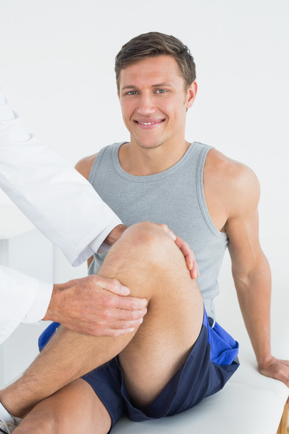Portrait of a young man getting his leg examined - Foto, imagen