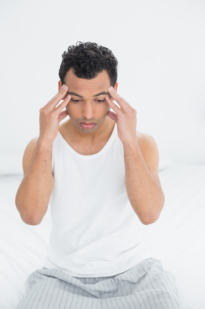 mens lijden hoofdpijn in bed - Foto, afbeelding