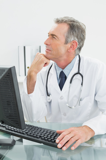 Doctor using computer at medical office - Фото, изображение
