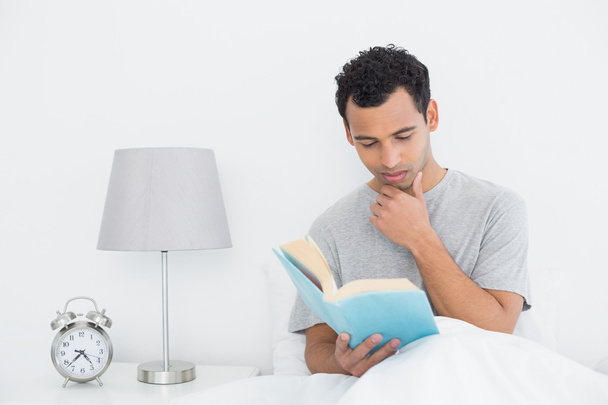 spokojny młody człowiek czytania książki w łóżku - Zdjęcie, obraz