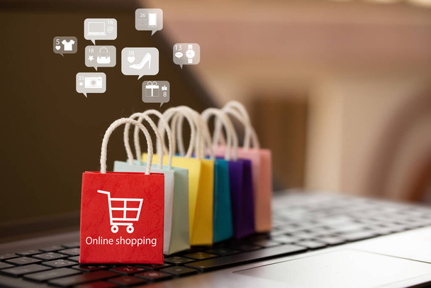 Online-Marketing und E-Commerce-Konzept: Einkaufstaschen aus Papier mit Icon Online-Shopping auf der Notebook-Tastatur. Der Kauf von Produkten und Dienstleistungen im Internet kann Waren bequem und sicher kaufen - Foto, Bild
