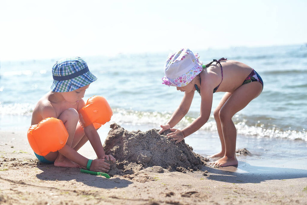 男の子も女の子も海のそばの砂浜で遊ぶ - 写真・画像