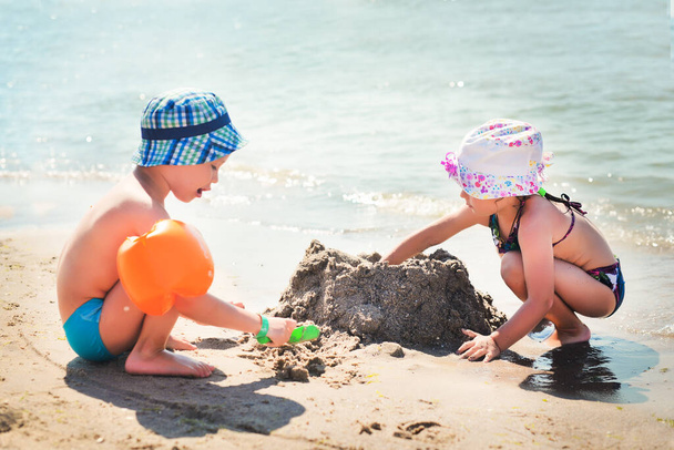 chłopiec i dziewczyna grać na piaszczystej plaży nad morzem - Zdjęcie, obraz