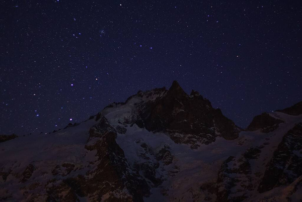 The dark sky full of stars over the snowy rocks - Fotografie, Obrázek