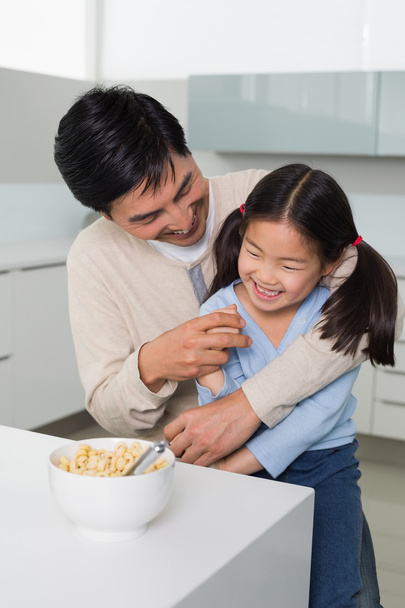 Joyeux père et fille ayant des céréales dans la cuisine
 - Photo, image