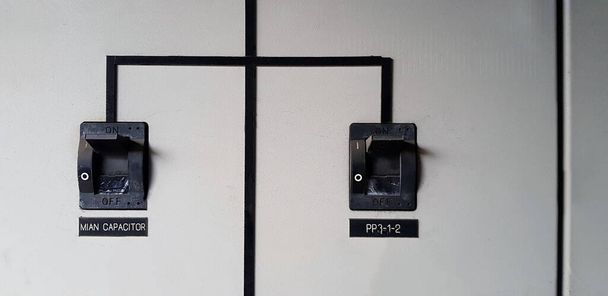 Primer plano Dos interruptores principales eléctricos negros se conectan entre sí en el gabinete de acero inoxidable gris o gris para la distribución de corriente eléctrica para cambiar o dispositivo con espacio de copia en la sala de energía
 - Foto, imagen
