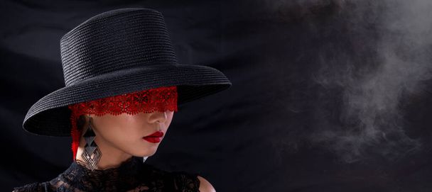Close up head shot of Fashion Young Asian Woman brown short hair beautiful cosmetic make up, tie red lace cover Eyes Face red lipstick, wear hat. Studio Lighting dark curtain Background copy space - Photo, Image