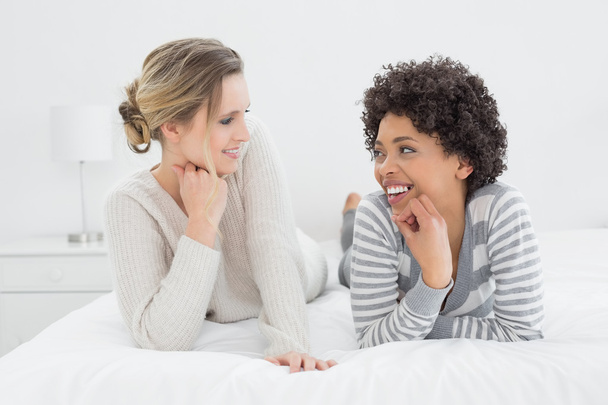Relaxed smiling female friends lying in bed - Foto, immagini