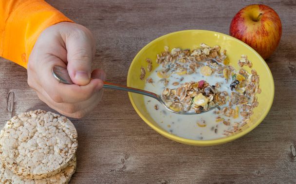 Friss müzli, müzli reggelire. Az ember tejjel eszi a gabonapelyhet egy tányérból. a megfelelő táplálkozás és az egészséges életmód koncepciója. Hasznos keverékek figyelemre méltó eltávolítása káros anyagok, salak. - Fotó, kép