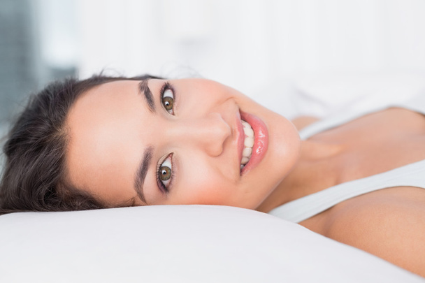 Close-up of a smiling pretty woman lying in bed - Fotó, kép