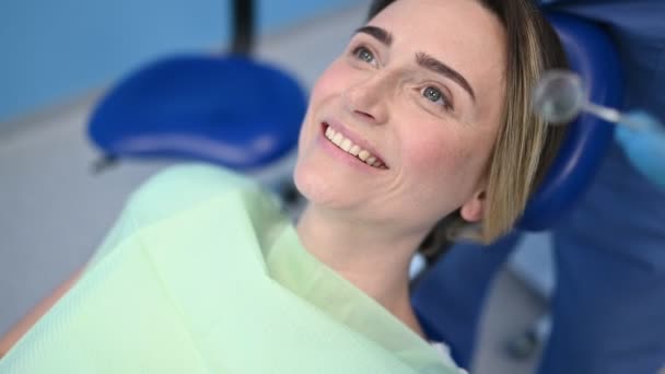 Dentista examinando los dientes de un paciente usando cuchara de impresión de equipo dental en la oficina de odontología. Concepto estomatológico y asistencial. Médico en mascarilla facial médica desechable, sonriendo mujer feliz
. - Imágenes, Vídeo
