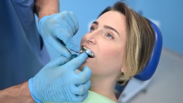 Tandarts maakt een siliconen gips van de tanden van de patiënt met behulp van tandheelkundige apparatuur afdruk lepel in tandheelkunde kantoor. Stomatologie en gezondheidszorg concept. Dokter in medische handschoenen, lachende gelukkige vrouw. - Video