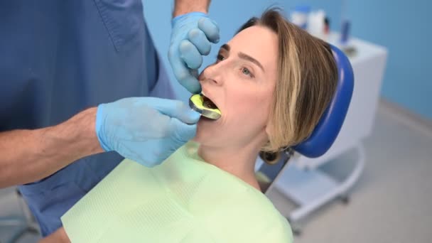 Hammaslääkäri tekee silikoni valettu potilaan hampaat käyttäen hammaslääkärin laitteet vaikutelma lusikka hammaslääketieteen toimistossa. Stomatologian ja terveydenhuollon käsite. Lääkäri lääketieteellisissä käsineissä, hymyilevä onnellinen nainen. - Materiaali, video